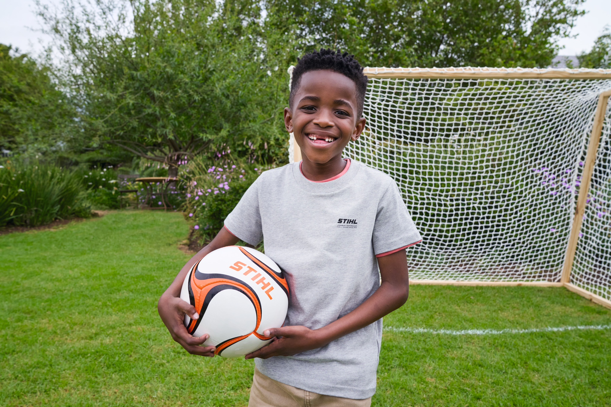 Een jongen staat voor het nieuwe voetbaldoel en houdt stralend een STIHL voetbal vast